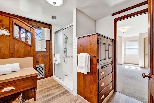 full bathroom with a stall shower, visible vents, wood finished floors, and wood walls