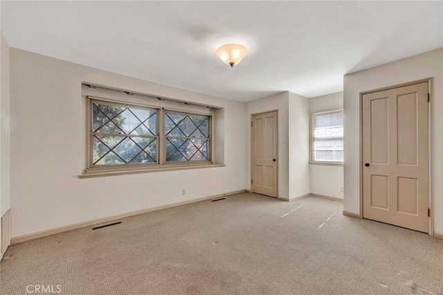 unfurnished bedroom with carpet flooring, visible vents, and baseboards