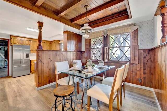 dining area with wooden ceiling, wooden walls, baseboards, light wood-style floors, and beam ceiling