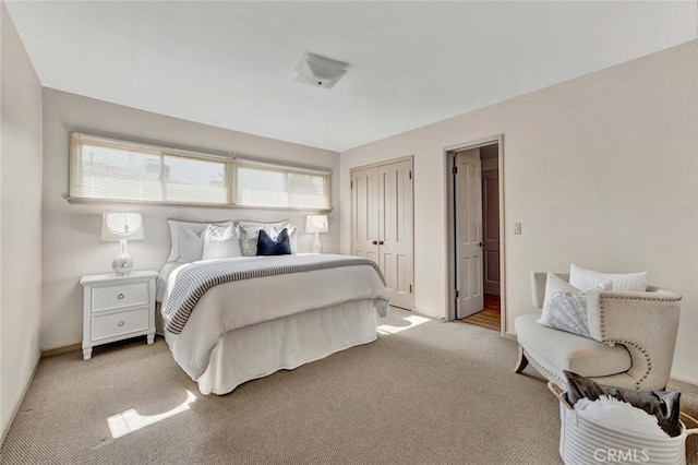 bedroom with baseboards, a closet, and light colored carpet