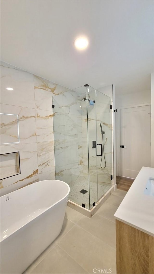 full bathroom with a freestanding bath, a marble finish shower, and vanity