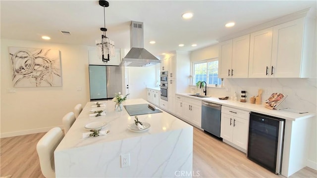 kitchen featuring island range hood, beverage cooler, stainless steel appliances, white cabinets, and pendant lighting