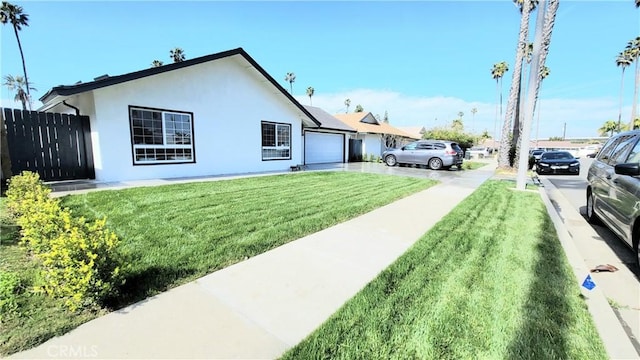 exterior space featuring a front lawn, an attached garage, fence, and stucco siding