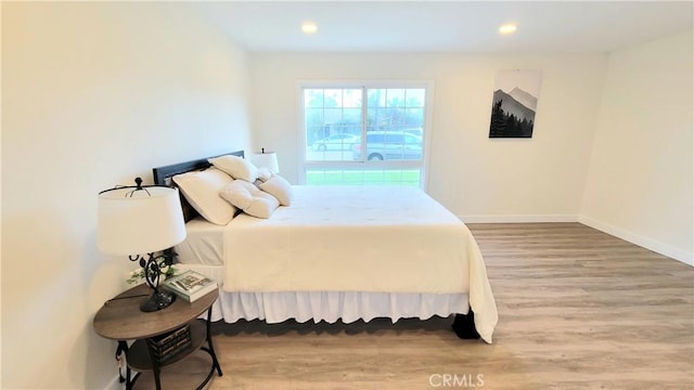 bedroom with recessed lighting, wood finished floors, and baseboards