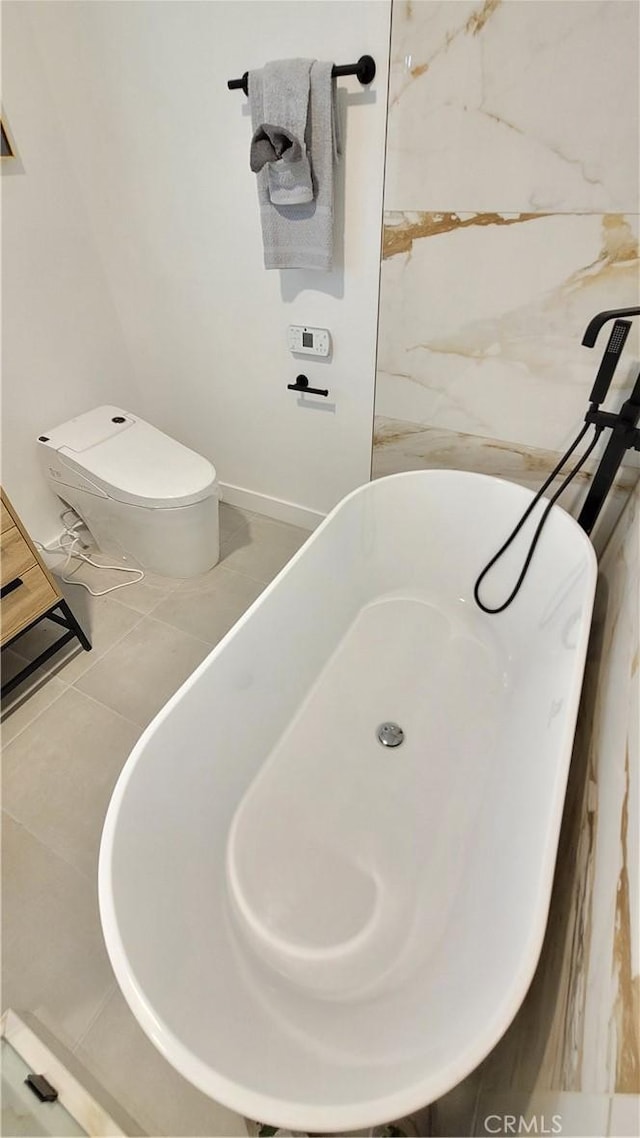 interior space with a soaking tub, toilet, and tile patterned floors