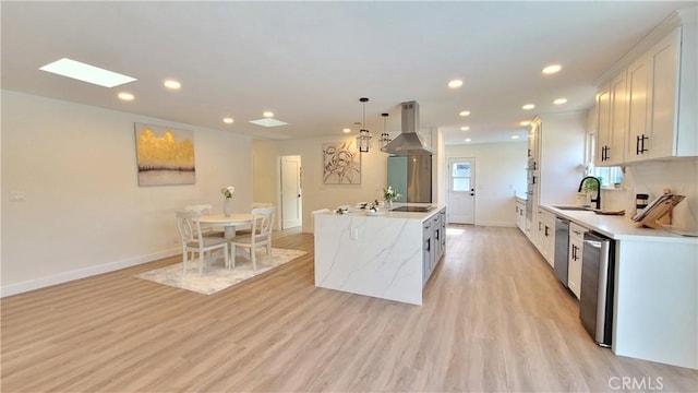 kitchen featuring pendant lighting, island exhaust hood, white cabinets, a kitchen island, and a sink