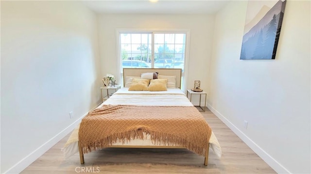 bedroom with light wood finished floors and baseboards