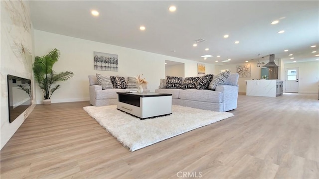 living area featuring recessed lighting, baseboards, and light wood finished floors