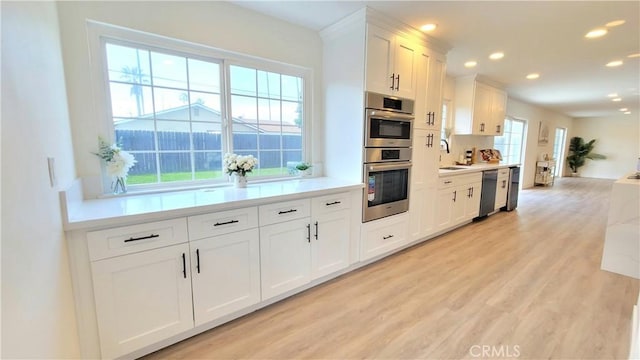 kitchen with appliances with stainless steel finishes, white cabinets, light countertops, and light wood finished floors