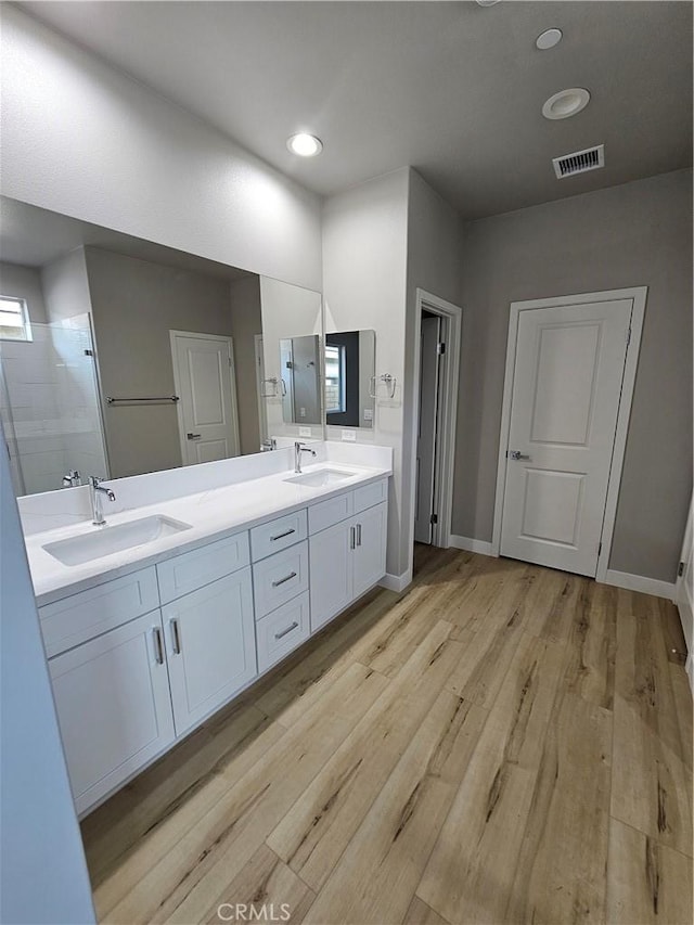 full bathroom featuring double vanity, visible vents, a sink, and wood finished floors