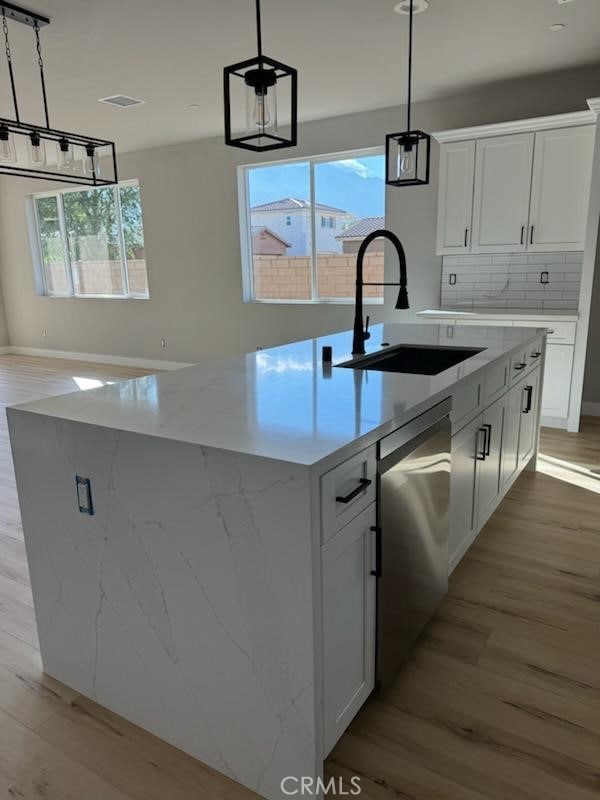 kitchen featuring dishwasher, a sink, and white cabinets