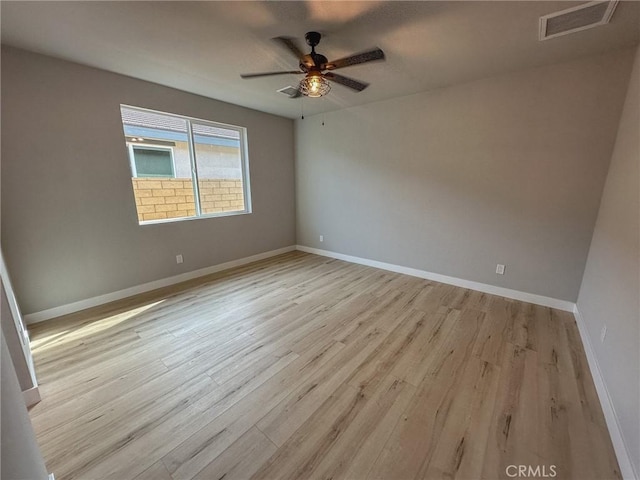 empty room with a ceiling fan, visible vents, light wood-style flooring, and baseboards