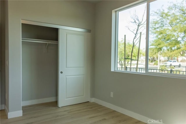 unfurnished bedroom with light wood finished floors, baseboards, and a closet