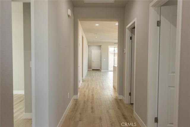 hall featuring light wood-type flooring, baseboards, and recessed lighting