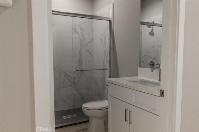 bathroom featuring toilet, a marble finish shower, and vanity