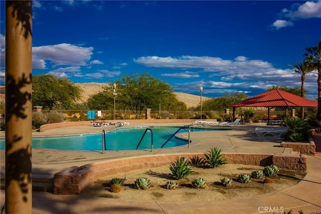 community pool with fence, a mountain view, a patio, and a gazebo