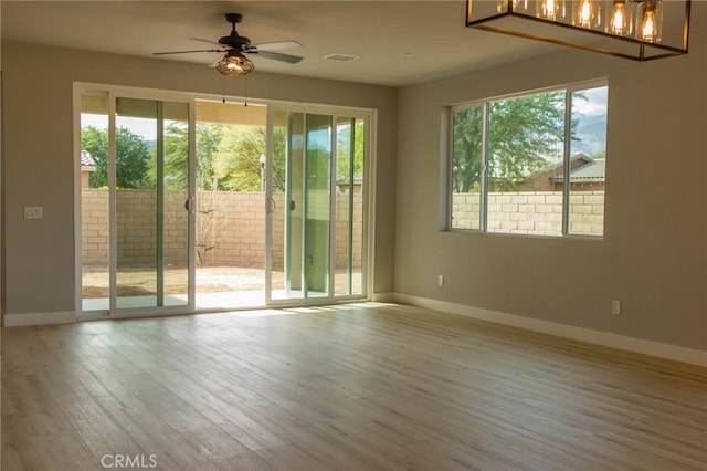 empty room with wood finished floors, a wealth of natural light, and baseboards