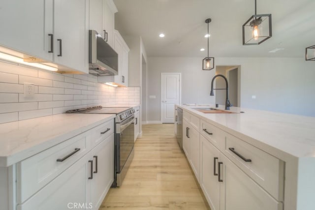 67813 Rio Vista Dr, Cathedral City, CA 92234 - kitchen featuring stainless steel appliances, light wood-style floors, decorative backsplash, white cabinetry, and a kitchen island with sink