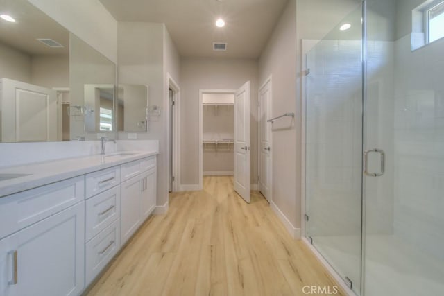 67813 Rio Vista Dr, Cathedral City, CA 92234 - bathroom featuring wood finished floors, double vanity, a stall shower, a walk in closet, and recessed lighting