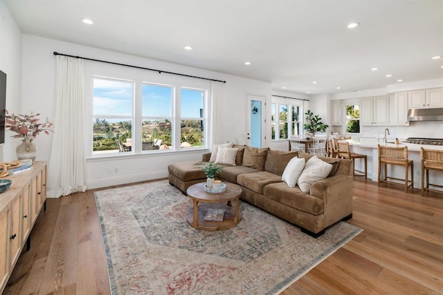 living room with baseboards, light wood-style flooring, and recessed lighting