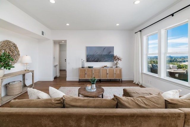 living room featuring visible vents, baseboards, wood finished floors, and recessed lighting