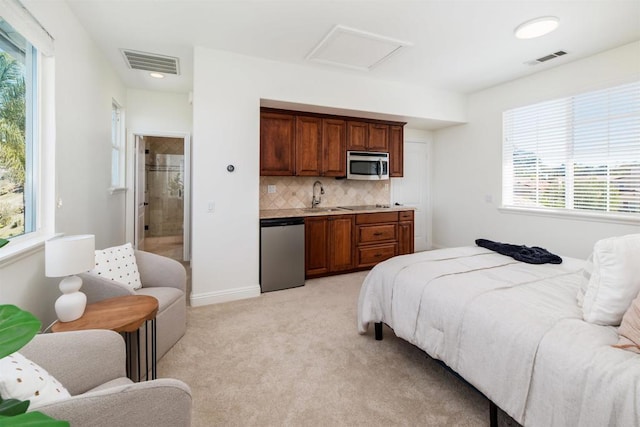 bedroom with attic access, light colored carpet, visible vents, and a sink