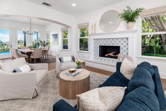 living room with visible vents, a fireplace, a notable chandelier, and wood finished floors