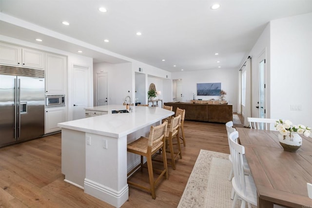 kitchen featuring built in appliances, a large island, recessed lighting, and light wood-style floors