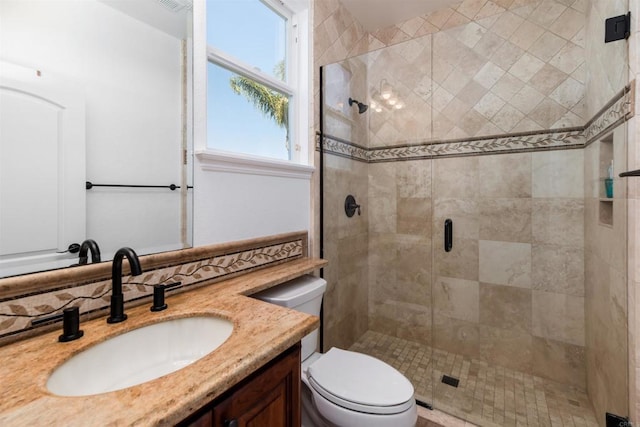 bathroom featuring toilet, a stall shower, and vanity