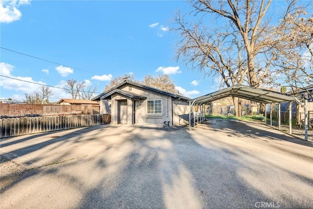 ranch-style home with driveway, a carport, fence, and stucco siding