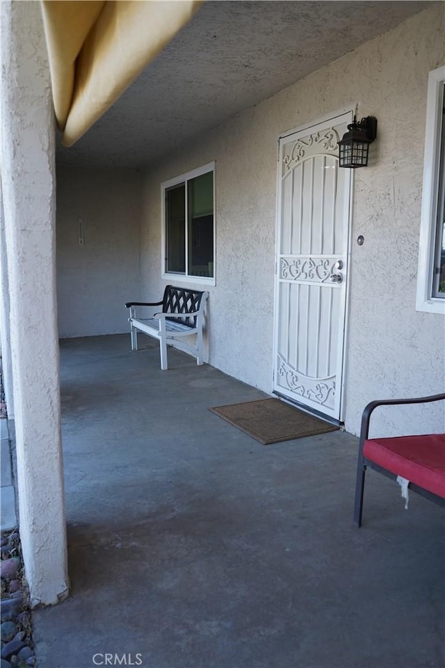 property entrance featuring stucco siding and covered porch