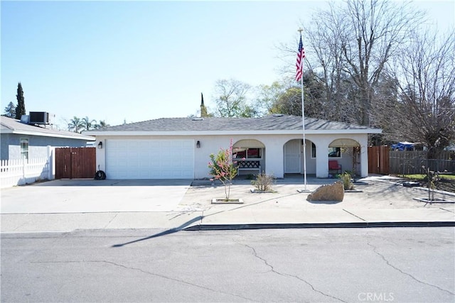 single story home with central AC unit, concrete driveway, a garage, and fence