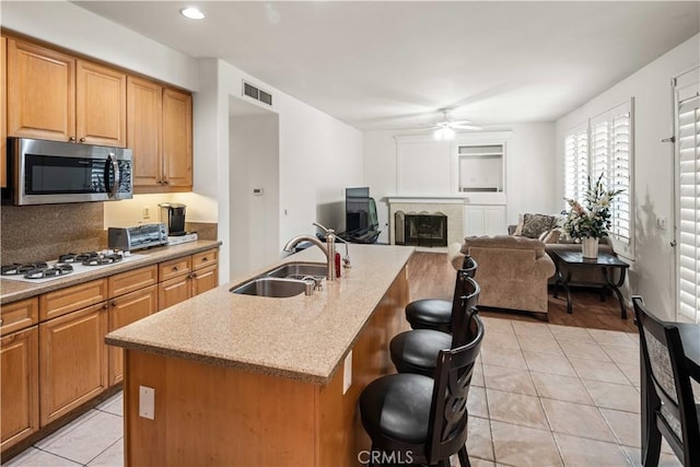 23718 Hathaway Dr, Valencia, CA 91354 - kitchen featuring stainless steel microwave, a sink, a ceiling fan, a breakfast bar area, and light tile patterned floors