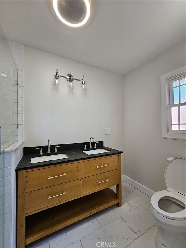 full bathroom with marble finish floor, tiled shower, a sink, and toilet