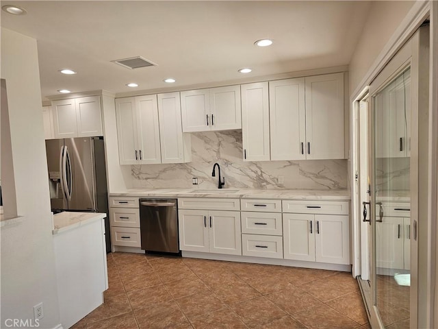 kitchen featuring appliances with stainless steel finishes, a sink, visible vents, and white cabinets