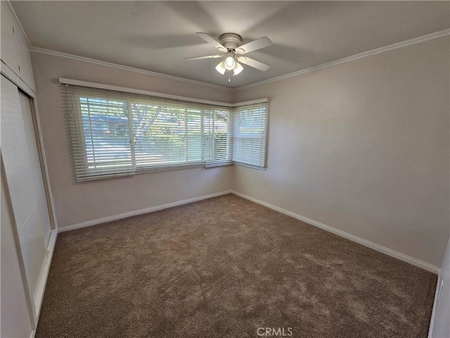 carpeted spare room with ceiling fan, ornamental molding, and baseboards