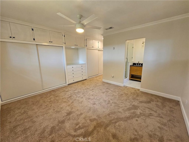 unfurnished bedroom featuring baseboards, visible vents, light colored carpet, ornamental molding, and ensuite bathroom