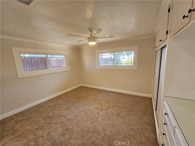 interior space featuring carpet floors, a ceiling fan, baseboards, a closet, and crown molding