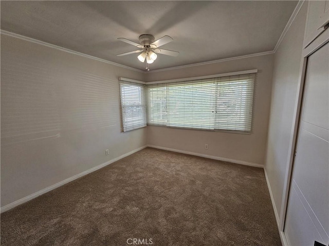 carpeted empty room featuring a ceiling fan, crown molding, and baseboards