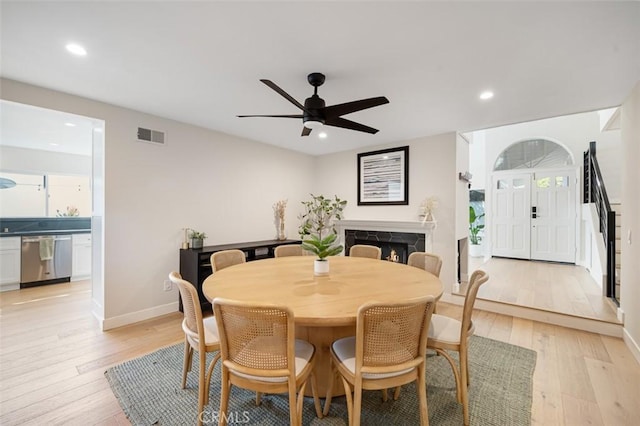 dining room featuring light wood-type flooring, a fireplace, and recessed lighting