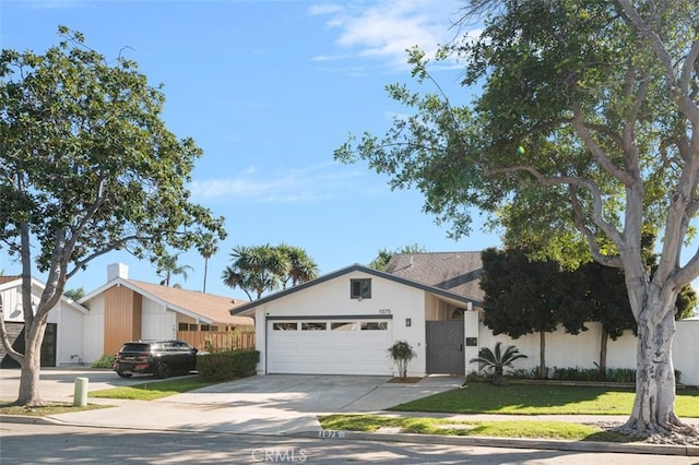 view of front of house featuring a garage, concrete driveway, fence, and stucco siding