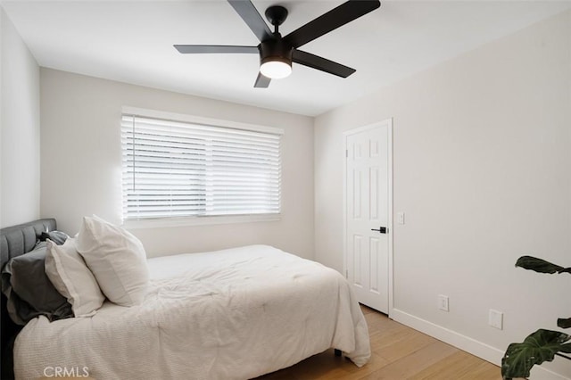 bedroom with light wood-type flooring, a ceiling fan, and baseboards