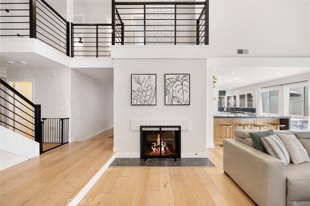 living room with a towering ceiling, wood finished floors, and visible vents