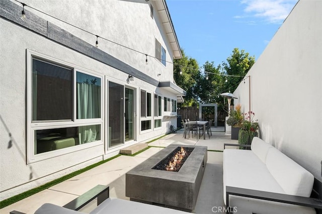 view of patio with outdoor dining area, an outdoor living space with a fire pit, and fence