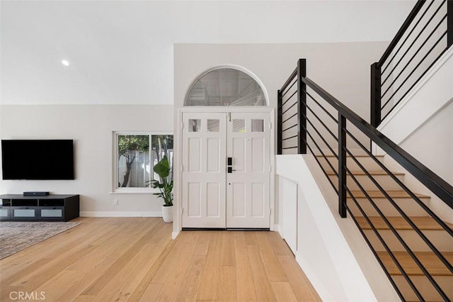 foyer entrance with light wood-style floors, baseboards, and stairs