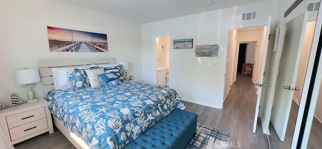 bedroom featuring ensuite bath, wood finished floors, visible vents, and baseboards