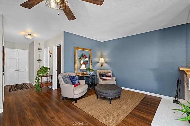 sitting room with a textured ceiling, wood finished floors, a ceiling fan, and baseboards