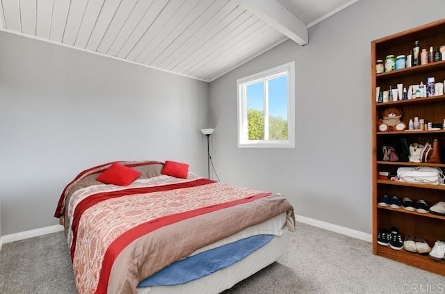 carpeted bedroom with wooden ceiling, vaulted ceiling with beams, and baseboards