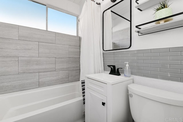 full bathroom with a sink, shower / tub combo, toilet, and tile walls