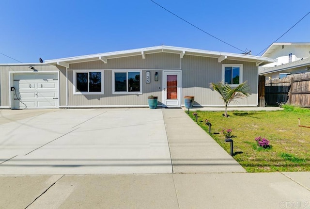 view of front facade featuring an attached garage, driveway, fence, and a front lawn